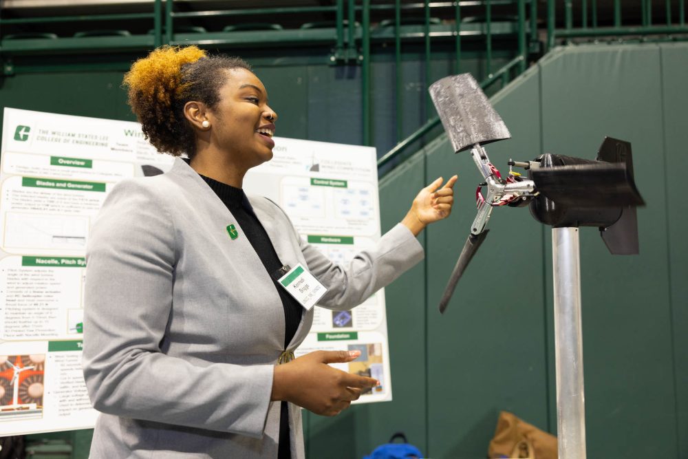 Senior engineering student demonstrates how wind turbine works during expo